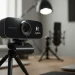 A professional Logitech MX Brio 4K webcam on a desktop tripod in a bright and clean content creator studio.