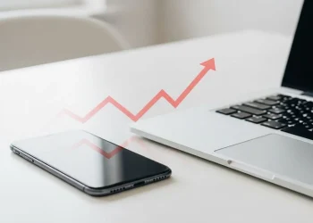 Smartphone and laptop with an upward trending arrow symbolizing the tariffs impact on technology and rising costs.
