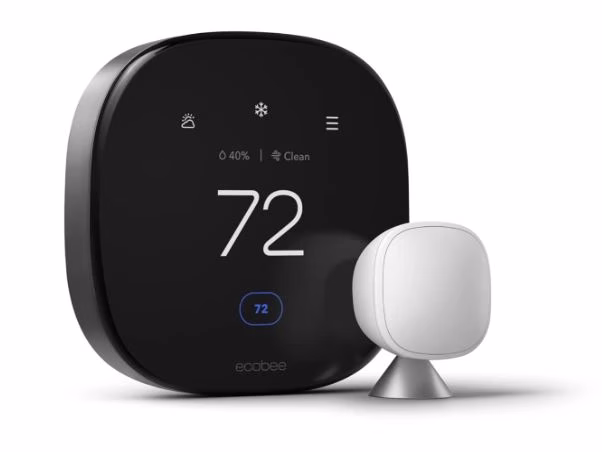 ecobee-smart-thermostat-premium The ecobee Smart Thermostat Premium mounted on a stylish wall, showing its large vibrant display, with the included SmartSensor placed on a nearby table.