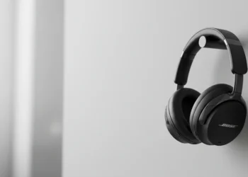 Black Bose wireless headphones hanging on a minimalist cylindrical wall mount.