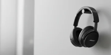 Black Bose wireless headphones hanging on a minimalist cylindrical wall mount.