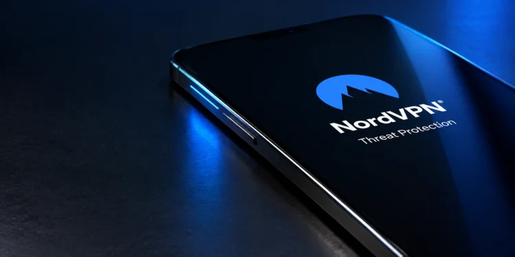 Smartphone lying flat on a dark table with NordVPN Threat Protection branding and sleek blue lighting.